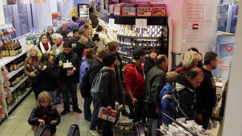 Eine Menschenmenge steht in einer langen Schlange in einem Supermarkt vor der Kasse