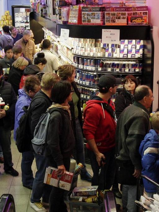 Eine Menschenmenge steht in einer langen Schlange in einem Supermarkt vor der Kasse