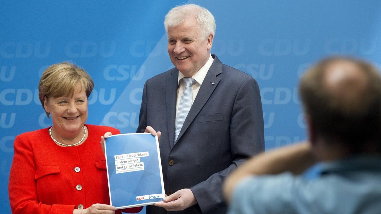 Merkel und Seehofer halten das Programm gemeinsam vor eine Kamera.