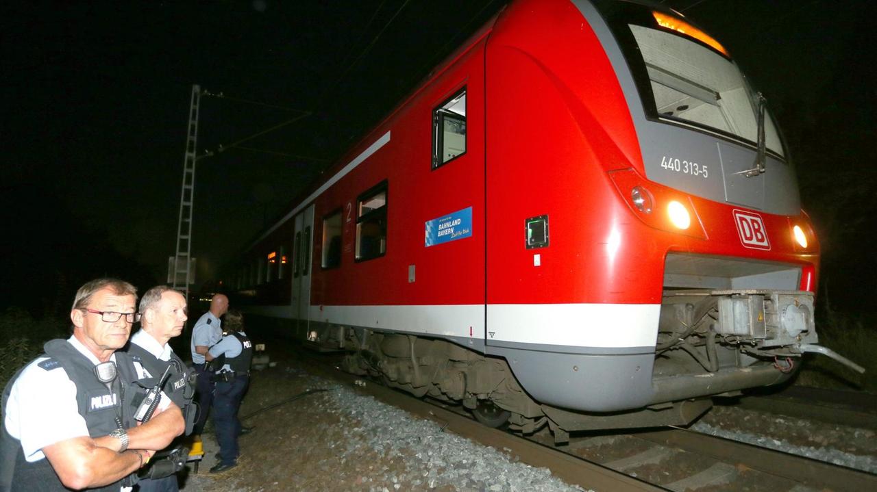 Polizisten stehen am 18.07.2016 bei Würzburg neben dem Zug, in dem ein 17-jähriger Asylbewerber mehrere Reisende mit einem Beil und einem Messer angriff und verletzte