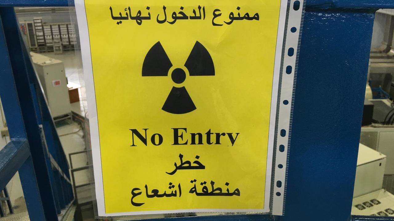 Ein gelb gefärbtes Blatt Papier, das in eine Folie gehüllt an einer blauen Rampe klebt. Darauf zu lesen ist in arabischer und englischer Sprache: "Kein Eingang". Zu sehen ist außerdem ein schwarzes Strahlenwarnzeichen.