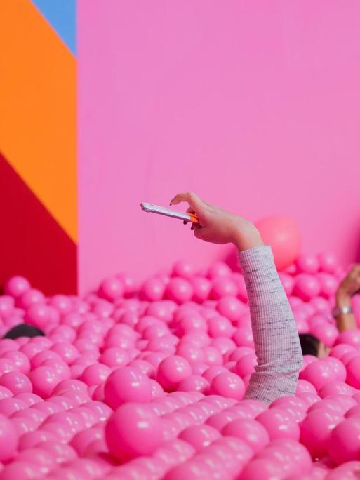 Besucherinnen machen im Supercandy Pop-Up Museum in einem Bällchenbad Selfies.