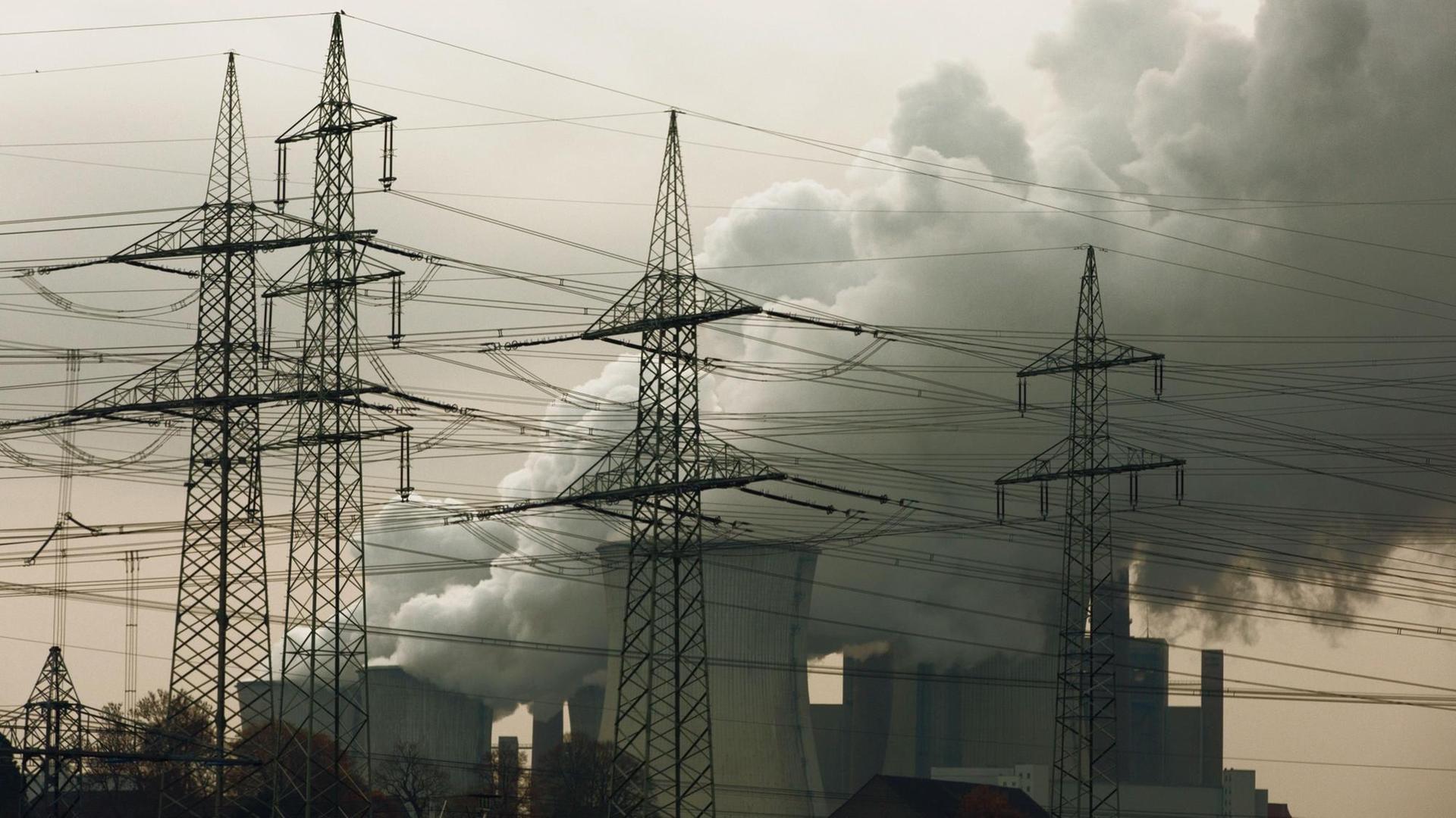 Dunkle Rauchwolken steigen aus einem Braunkohlenkraftwerk in den Himmel auf.