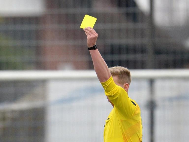 Der Schiedsrichter zeigt am 14.03.2015 bei einem Fußballspiel in eine gelbe Karte.
