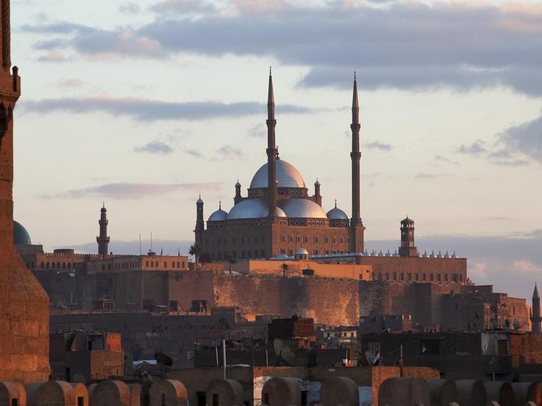 Blick vom Dach der Mu'ayyad Moschee durch die über dem Stadttor Bab Zuweila aufragenden Minarette auf die Zitadelle mit Kairos Wahrzeichen, der Mohammed Ali Moschee.