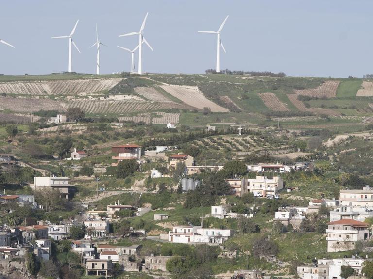 Windräder stehen über einem Bergdorf auf Kreta.