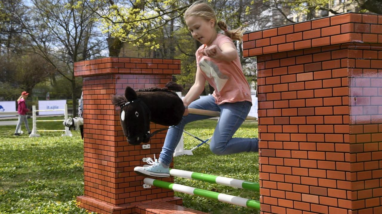 Ein Mädchen springt mit seinem Steckenpferd über ein Hindernis bei einem "Hobby Horsing"-Turnier in Helsinki.