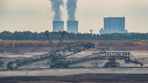 Ein Schaufelradbagger steht im Braunkohletagebau Welzow-Süd der Lausitz Energie Bergbau AG (LEAG). Dahinter steigt Wasserdampf aus den Kühltürmen des Braunkohlekraftwerkes Schwarze Pumpe.