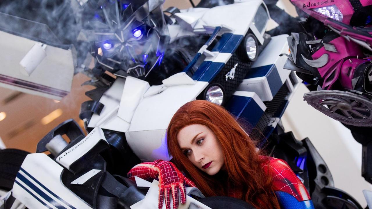 Eine Cosplayerin steht auf der Comic und Filme-Messe "Comic Con Experience" (CCXP) zwischen zwei Figuren aus dem Film Transformers.
