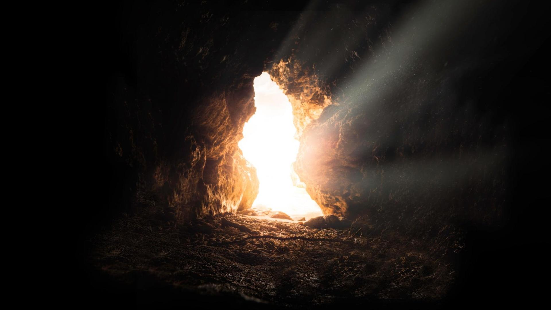 Eingang einer einsamen Höhle, Aufnahme aus dem Inneren. Ein heller Lichtstrahl strömt hinein.