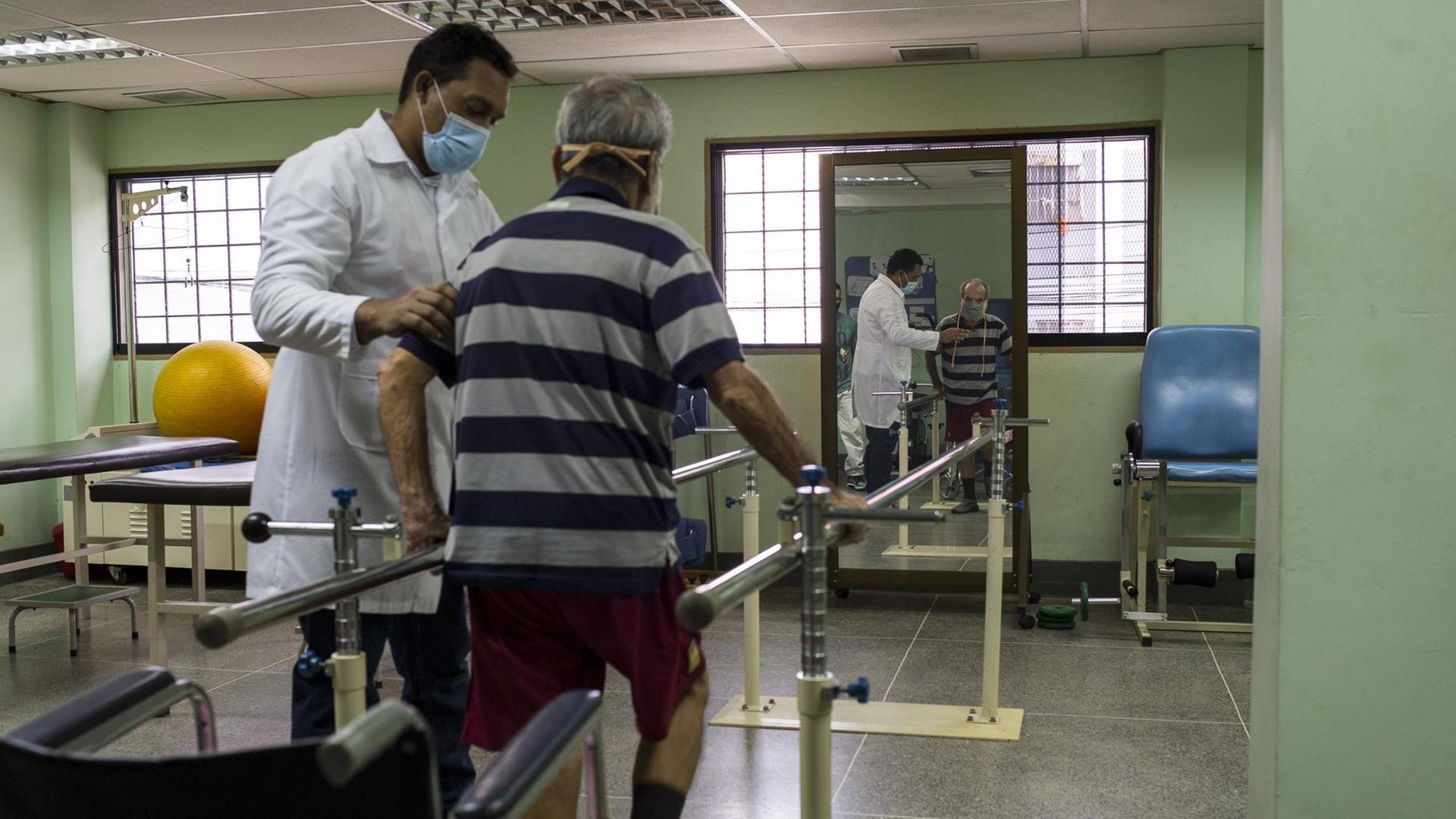 Der 78-jährige Eduardo Ortiz (l) macht Übungen mit Fachkräften eines von der Regierung betriebenen Reha-Zentrums für Covid-19-Patienten in Venezuela.
