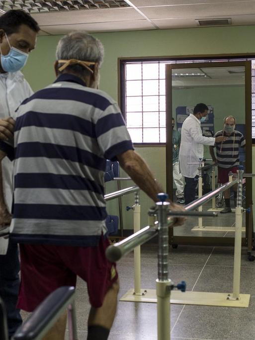 Der 78-jährige Eduardo Ortiz (l) macht Übungen mit Fachkräften eines von der Regierung betriebenen Reha-Zentrums für Covid-19-Patienten in Venezuela.