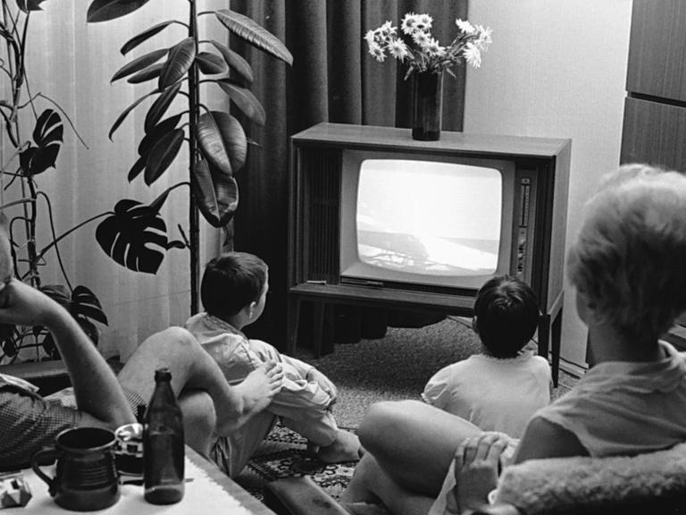 Die Familie sitzt im Schlafanzug vor dem Bildschirm, beobachtet die Mondlandung von Apollo 11. Das Bild ist schwarz-weiß.