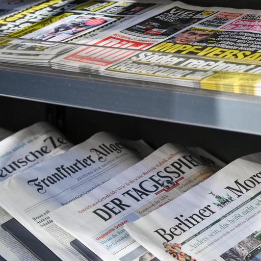 Zeitungen liegen in einer Auslage in einem Zeitschriftenladen.