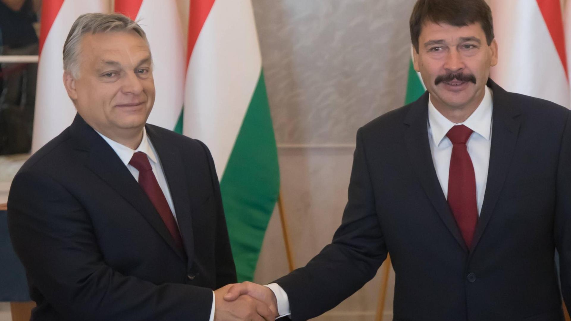 Shakehands zwischen Orban und Ader vor ungarischen Flaggen