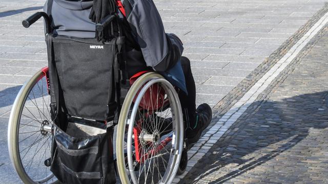 Ein Roll-Stuhl-Fahrer ist auf einer Straße unterwegs.