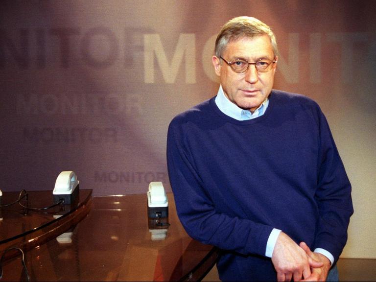 Ein Mann in Hemd und blauem Pullover steht in einer altmodischen Fernsehstudiokulisse: Es ist der damalige Redaktionsleiter des WDR-Politmagazins "Monitor": Klaus Bednarz.