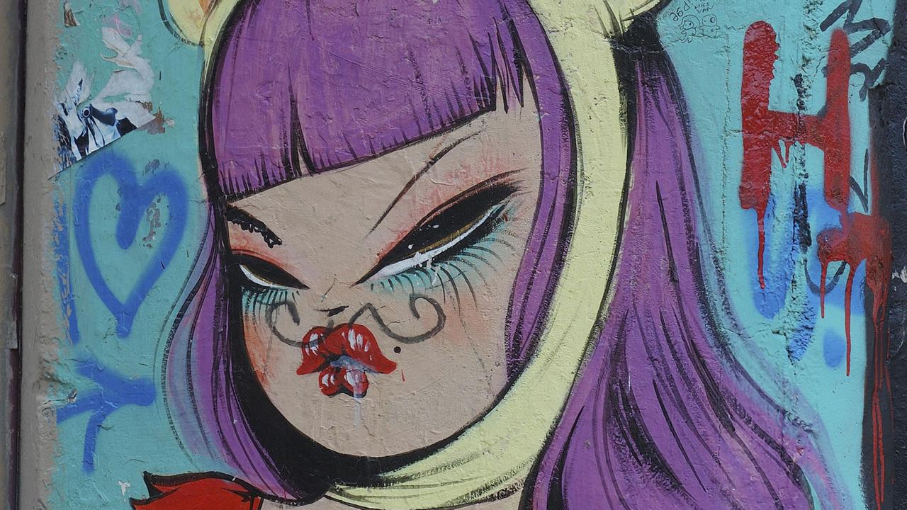 Das Graffito in Barcelona zeigt eine Comicfigur mit lila Haaren.