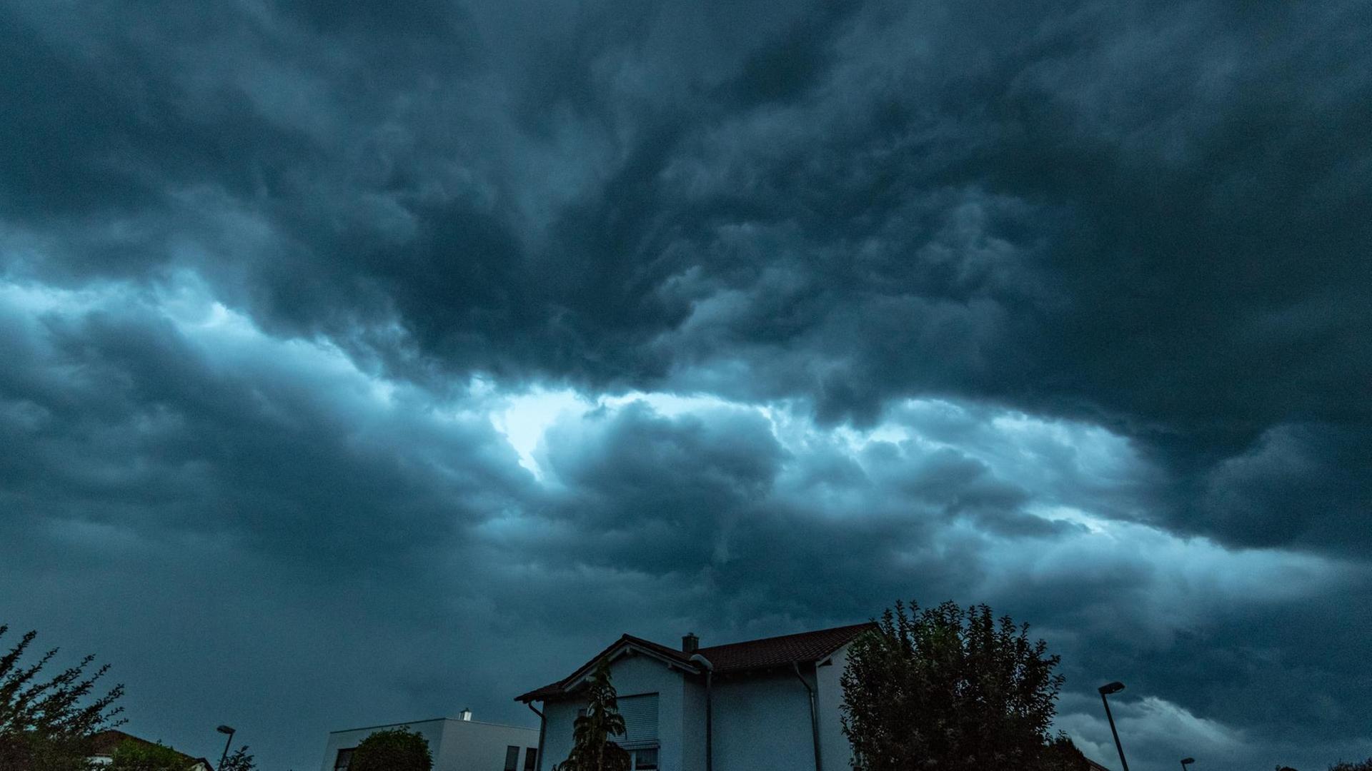 Bayern, Straubing: Dunkle Gewitterwolken ziehen im Abendlicht über ein Wohngebiet.