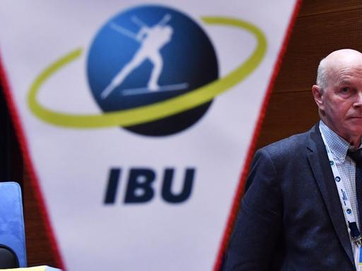 Anders Besseberg hinter einem Wimpel mit dem Logo der International Biathlon Union.
