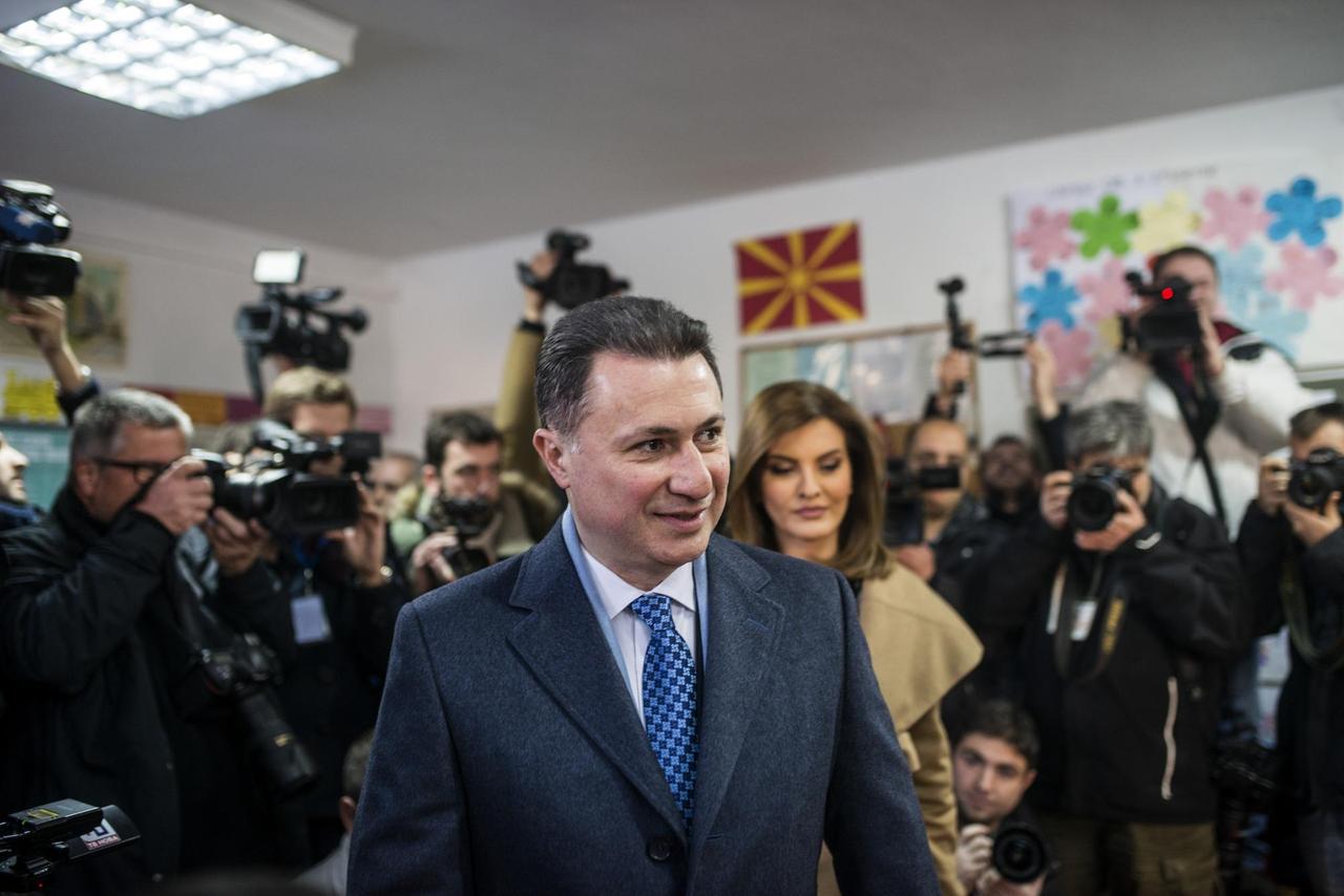 Mazedoniens langjähriger Ministerpräsident Nikola Gruevski in blauem Anzug, hinter ihm eine Frau und mehrere Fotografen.