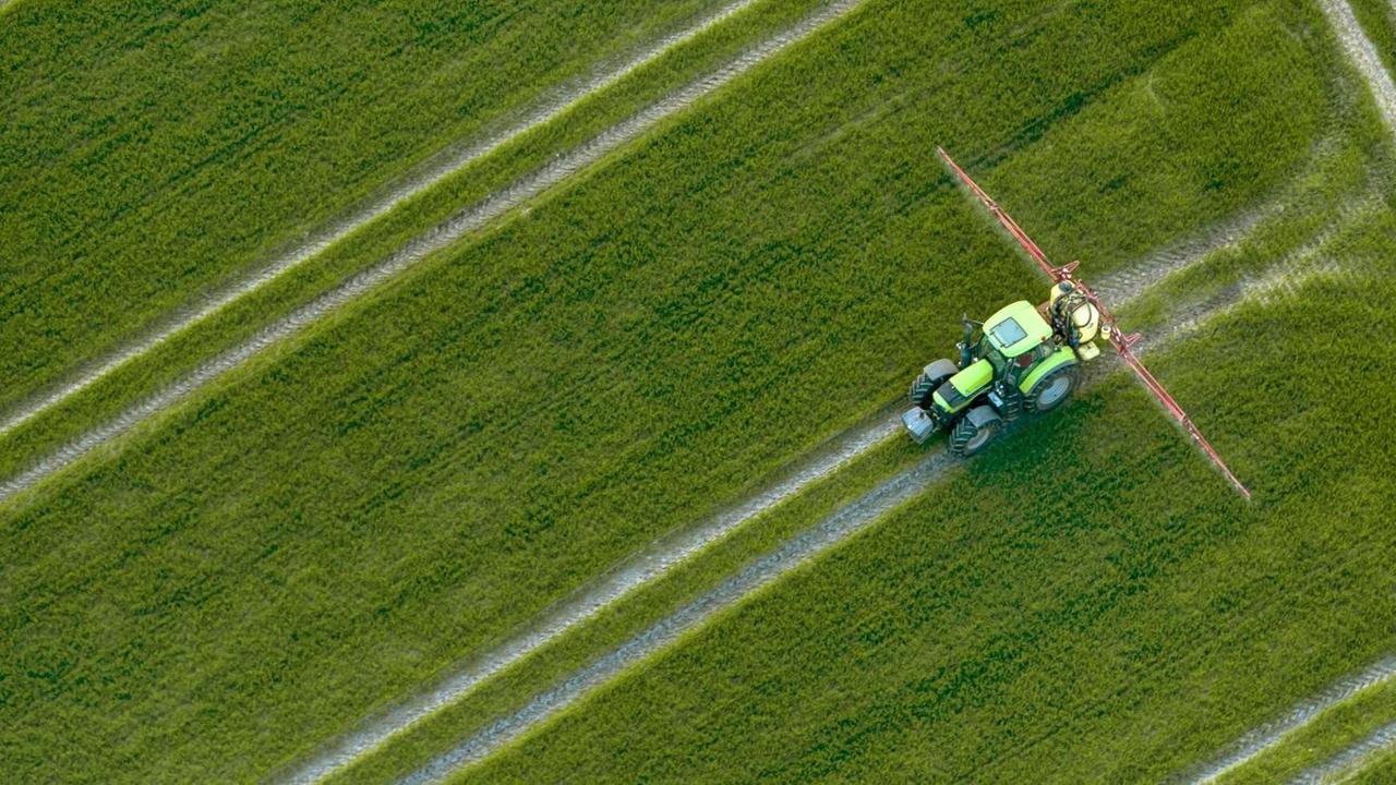 Luftaufnahme eines Traktors, der Pestizide über ein Feld versprüht