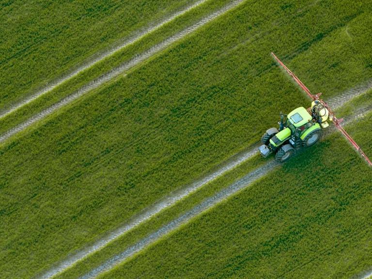 Luftaufnahme eines Traktors, der Pestizide über ein Feld versprüht