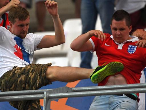 Ein russischer Fan tritt einem englischen Fan gegen den Bauch.