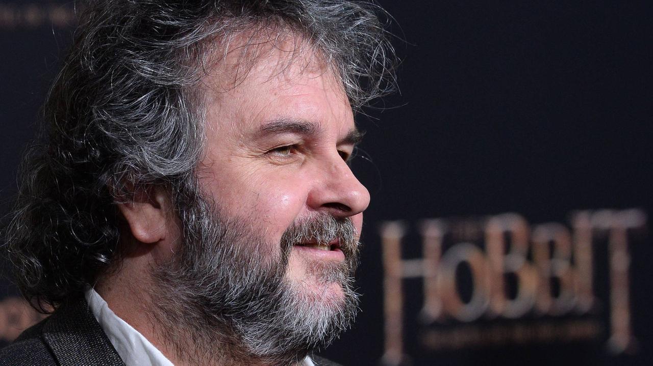 Regisseur Peter Jackson steht vor einem Filmplakat mit der Aufschrift Hobbit