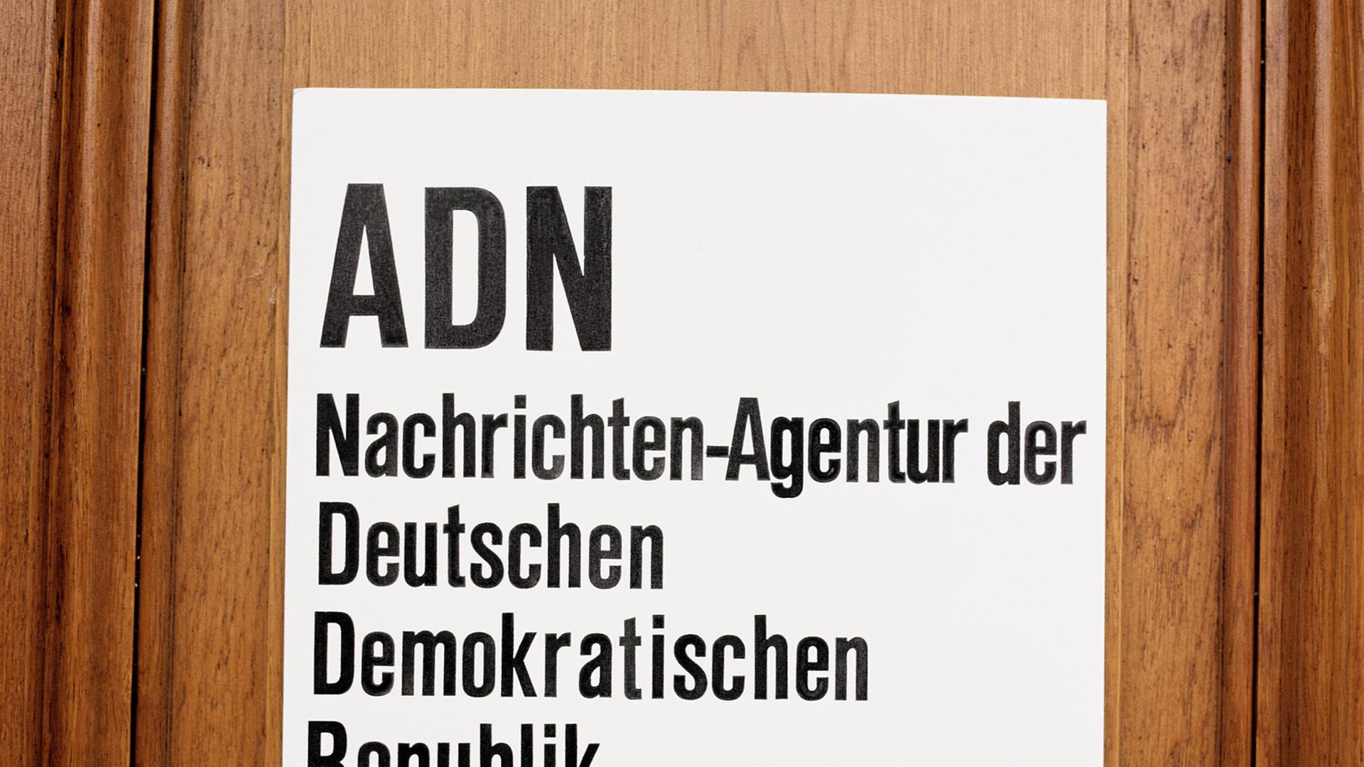 Das Schild: ADN Nachrichten-Agentur der Deutschen Demokratischen Republik ist zu sehen