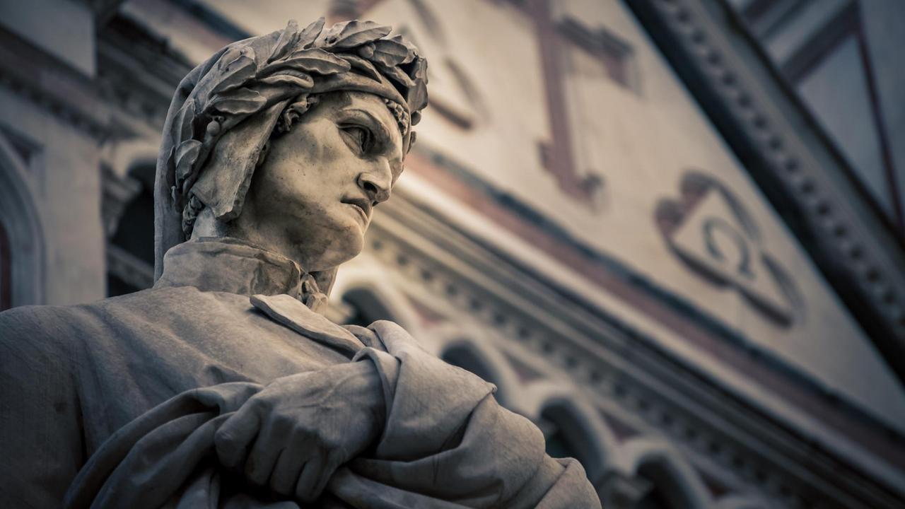 Blick von unten auf das Gesicht der Dante-Statue von Florenz, das vor einem historischen Kirchengebäude steht.