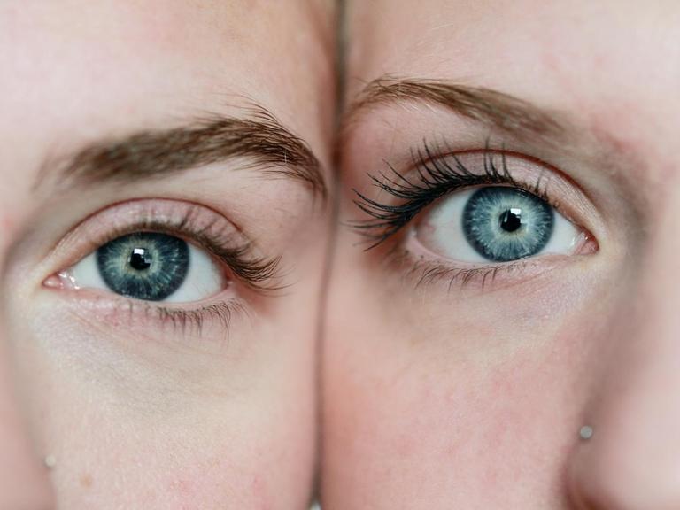 Zwei helle Gesichtshälfen sin im Anschnitt bis zur Nase zu sehen. Je ein blaues Auge blickt direkt in die Kamera.
