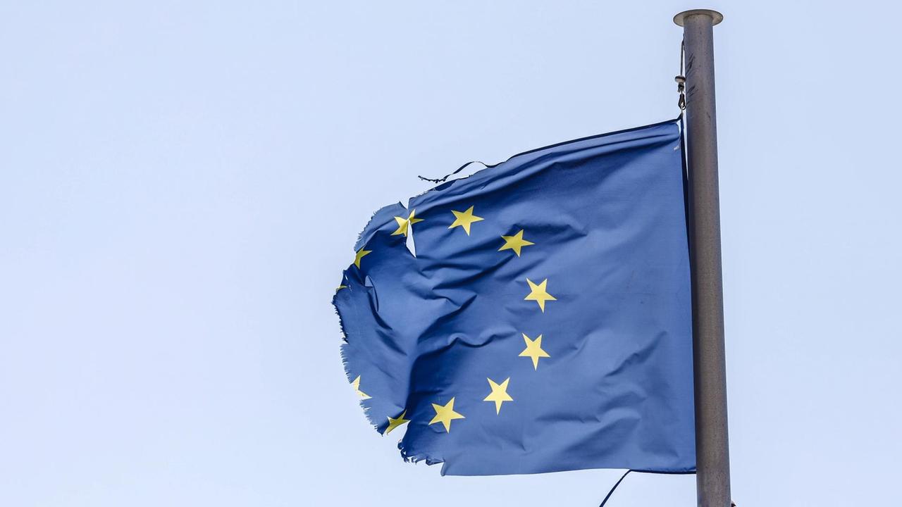 Eine zerrissene EU-Fahne flattert im Wind.