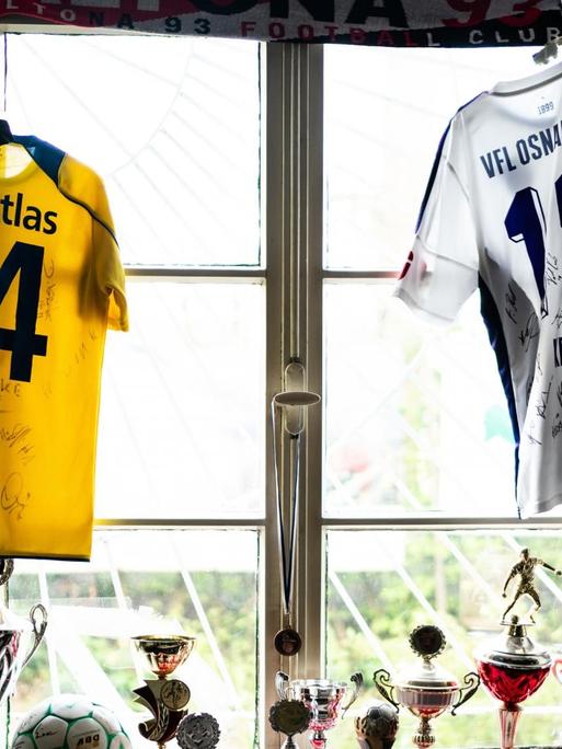 Ein Fußballfan hat all seine Pokale und Trikots vom SV Atlas Delmenhorst und vom VfL Osnabrueck im Fenster drapiert.