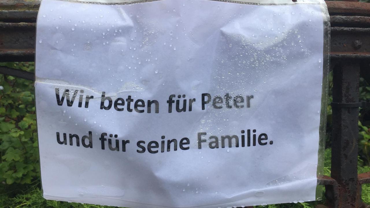 Ein Blatt mit der Aufschrift "Wir beten für Peter und für seine Familie" hängt vor der Gethsemanekirche.