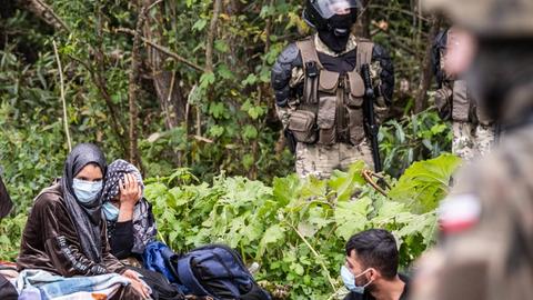Flüchtlinge aus Afghanistan an der Grenze zwischen Belarus und Polen unter Beobachtung von polnischen Sicherheitskräften