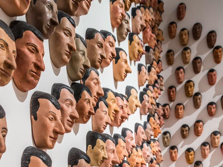 Besucherin der Ausstellung "Unendlicher Spaß" in der Frankfurter Schirn betrachtet Maurizio Cattelans "Spermini". Die Arbeit besteht aus 250 bemalten Gummimasken.