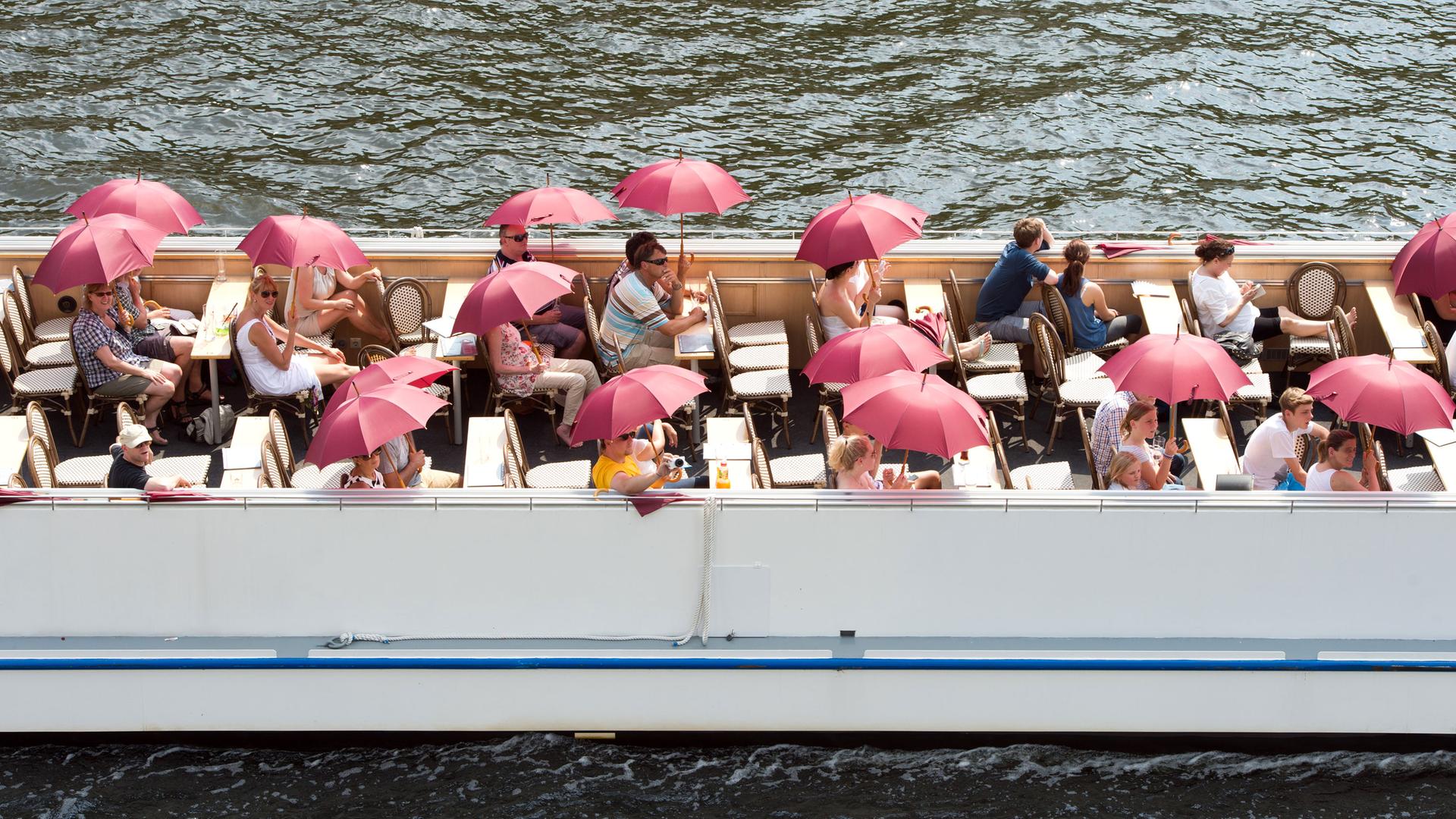 Touristen mit Schirmen auf einem Ausflugsschiff