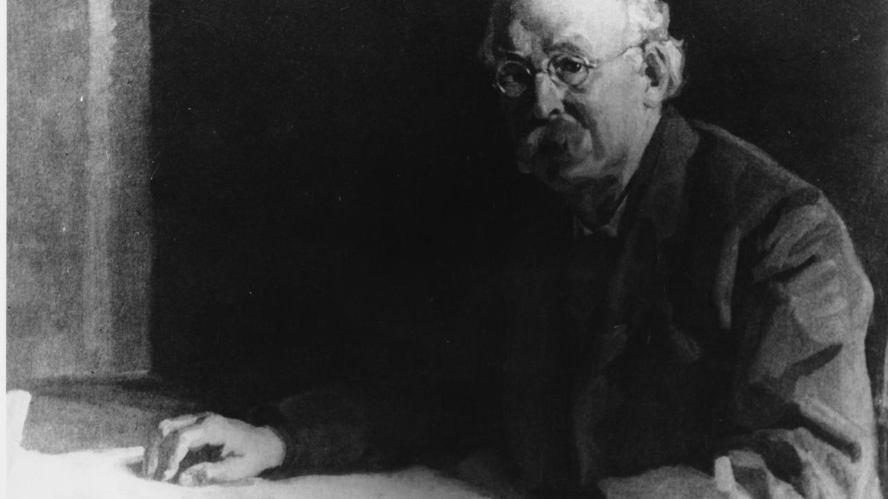 Undatiertes Bild des Stadtplaners und Mitbegründers der Gartenstadt Ebenezer Howard. Ein alter Mann sitzt an einem Tisch.