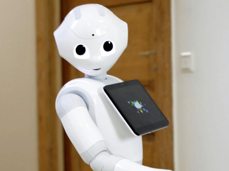 Ein humanoider Roboter mit Kulleraugen und einem integrierten Tablet.