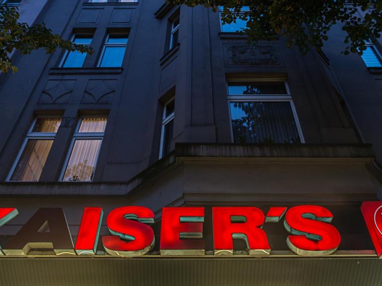 Die Leuchtbuchstaben einer Kaiser's-Filiale hängen in Düsseldorf an einem Gebäude.