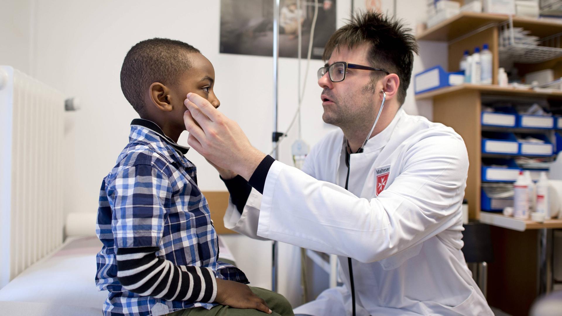 Ein Arzt untersucht in seiner Praxis einen Jungen.