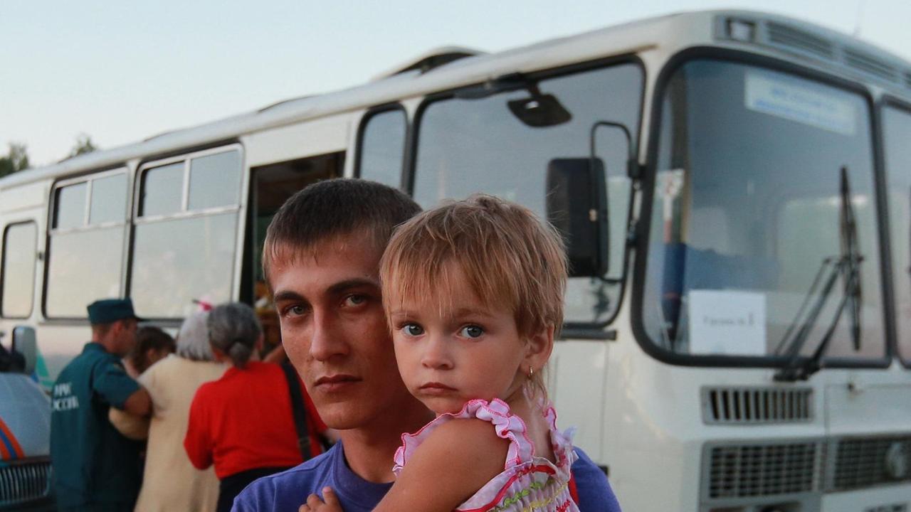 Ein Ukrainier und seine Tochter warten darauf zu temporären Flüchtlingsunterkünften in Russland ausgeflogen zu werden.