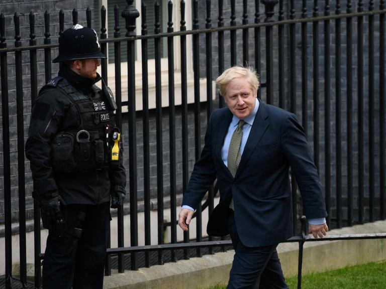 Premierminister Boris Johnson läuft vor Downing Street 10 an einem Wachpolizisten vorbei.