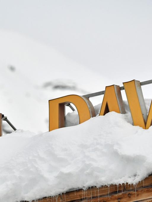 Ein Polizist in Tarnkleidung steht mit einem Maschinengewehr auf einem Dach mit der Schrift "Hotel Davos".