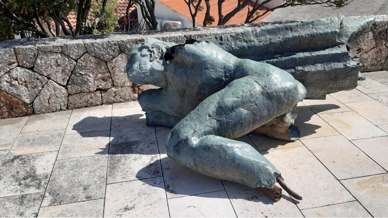 Eine Skulptur, die einen Partisanen aus dem Zweiten Weltkrieg zeigt, liegt gestürzt auf hellem Pflaster.