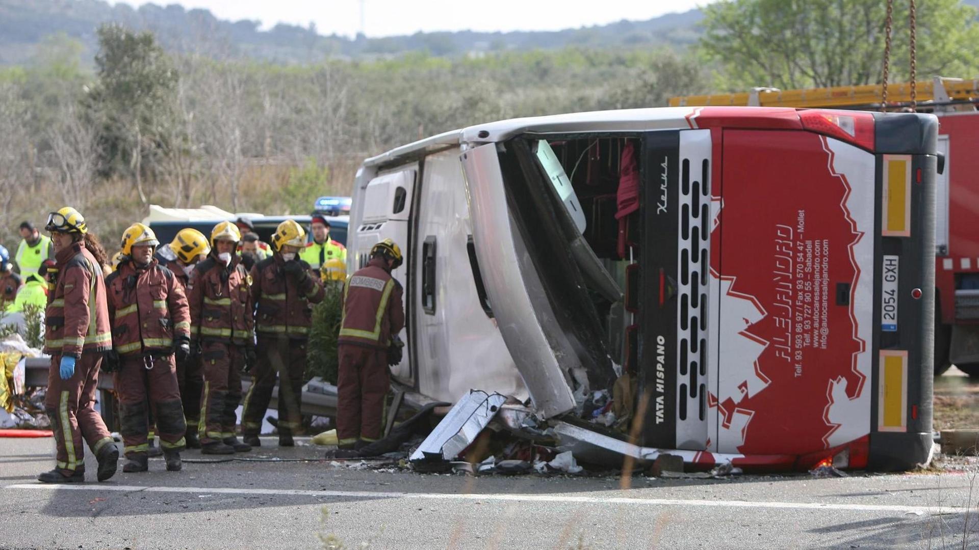 Feuerwehrmänner stehen neben dem umgestürzten Bus auf der Autobahn nahe der spanischen Stadt Freginals. Feuerwehrmänner stehen neben dem umgestürzten Bus auf der Autobahn nahe der spanischen Stadt Freginals.