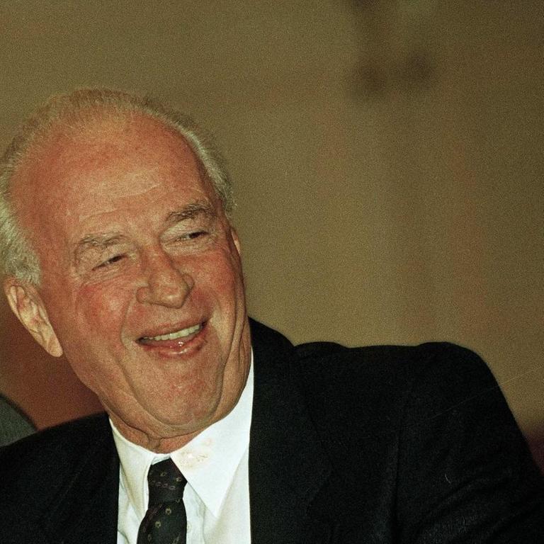 Der ehemalige israelische Ministerpräsident Yitzhak Rabin lächelt und hält bei einem Hoteldinner in Israel eine Zigarette in der Hand