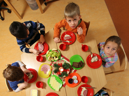 Kinder sitzen beim Frühstück in einer Kindertagesstätte.