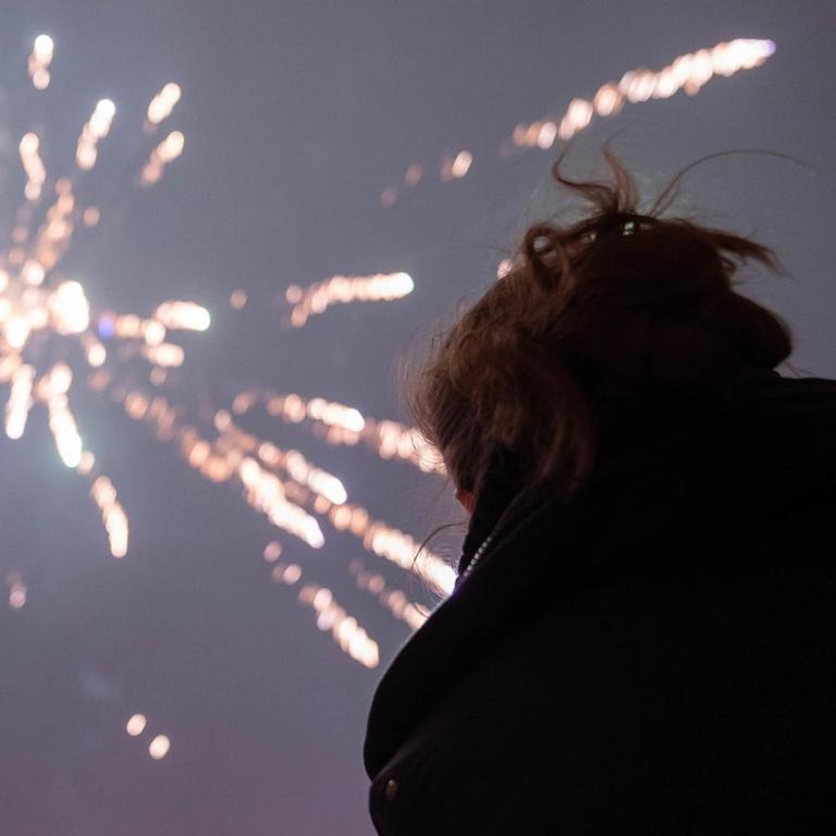 Eine Frau schaut sich am 01.01.2019 in Berlin das Silvesterfeuerwerk an (gestellte Szene). 